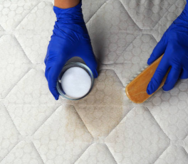 Man sprinkling baking soda over bed sheets to remove odors and freshen up the mattress