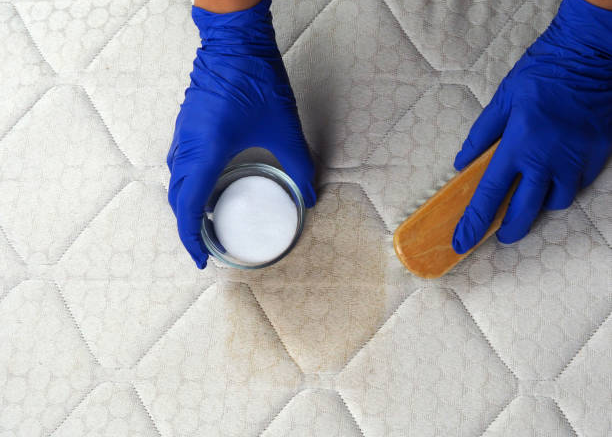 Man sprinkling baking soda over bed sheets to remove odors and freshen up the mattress